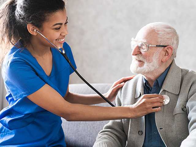 Healthcare provider listening to man's heart.