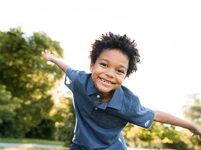 Child with arms wide outside.