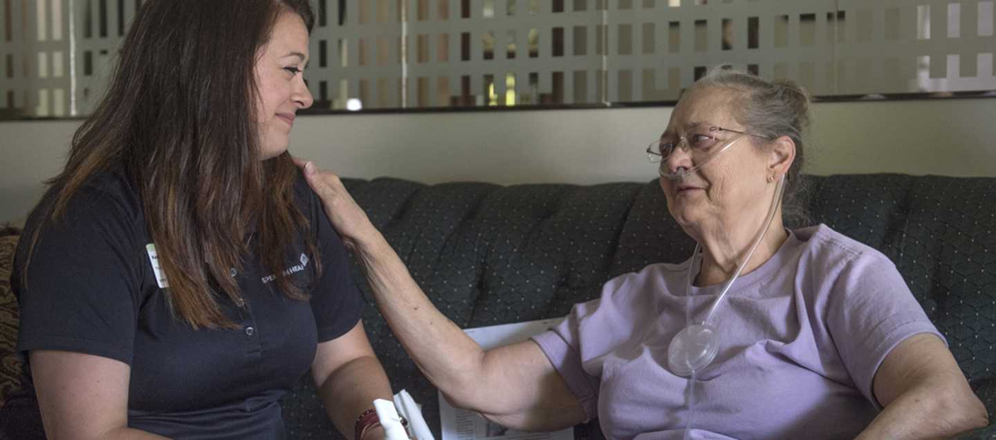 Elderly patient puts hand on shoulder of nurse.