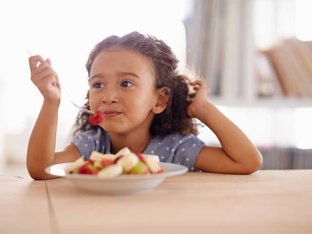 Young girl eating sliced apples.